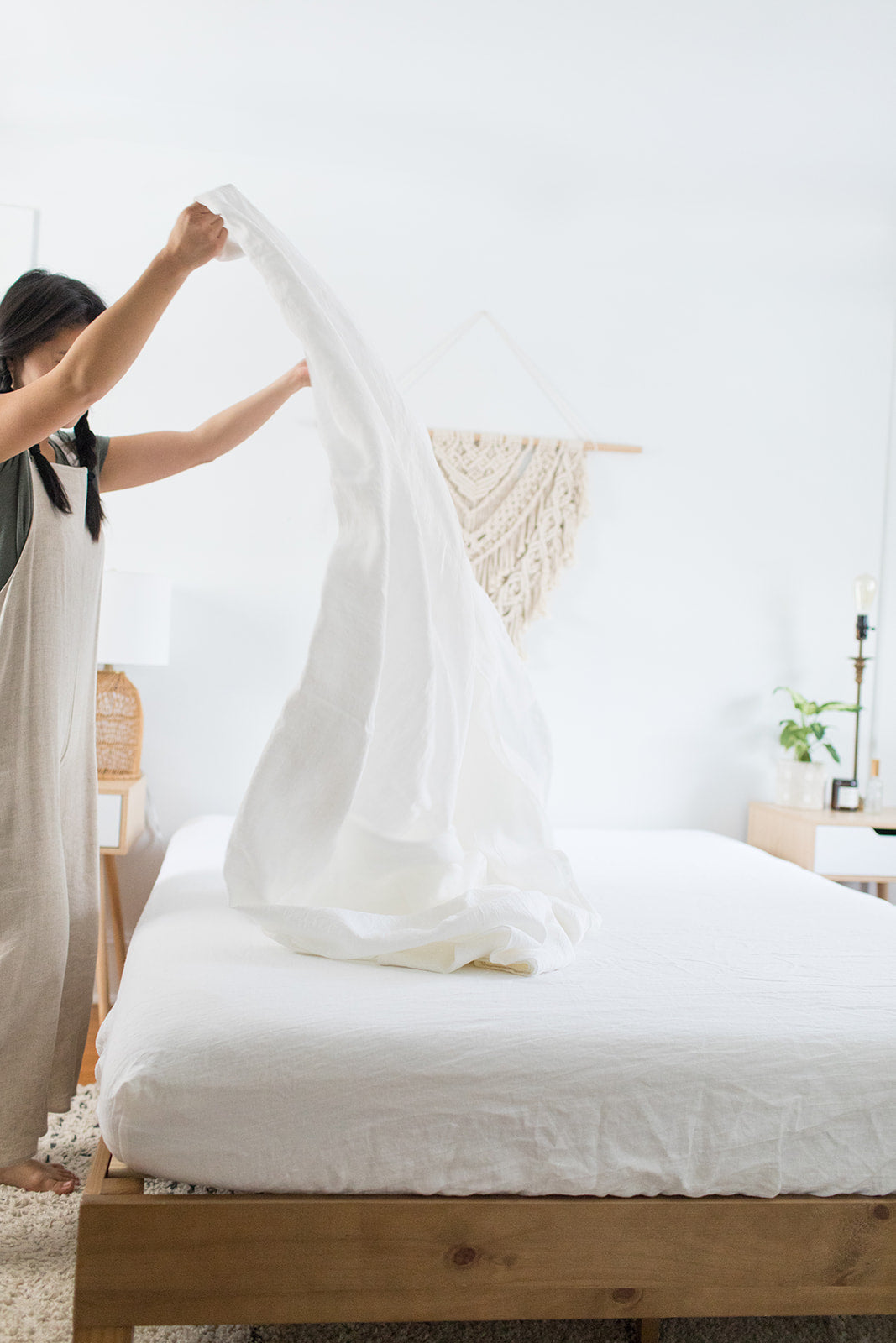 Person making bed with soft white linen sheets