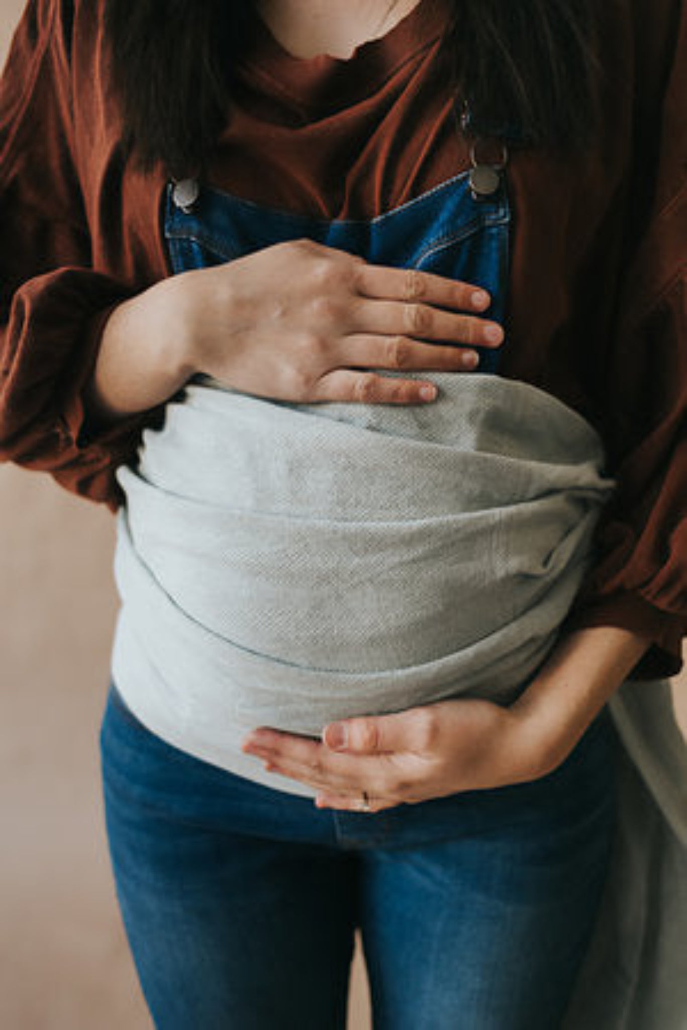 Person holding a gray baby wrap against a neutral background