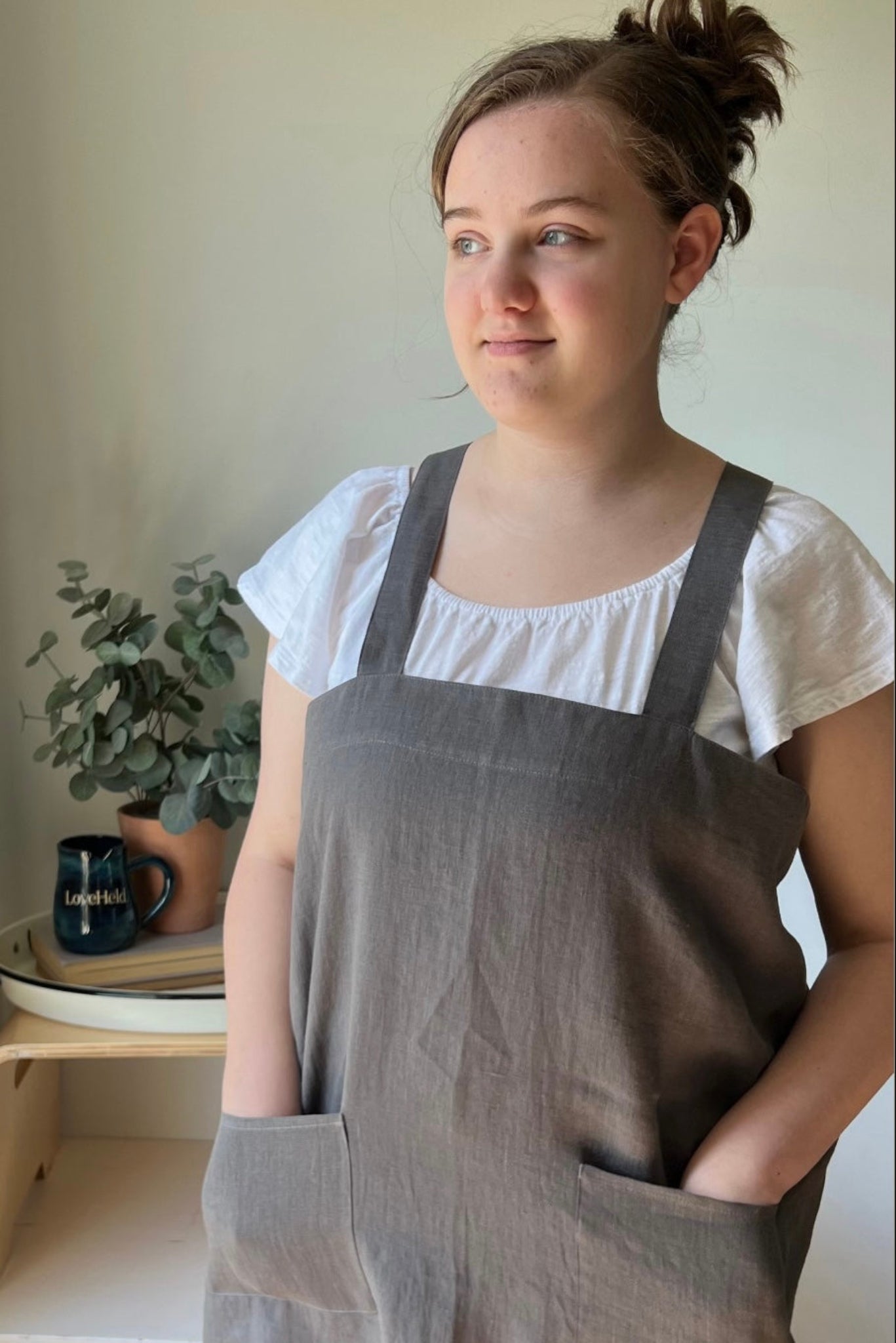 A kitchen scene with a beige apron laid out flat, surrounded by chocolate chips, a whisk, and a bowl of brown sugar, with a green napkin at the top.