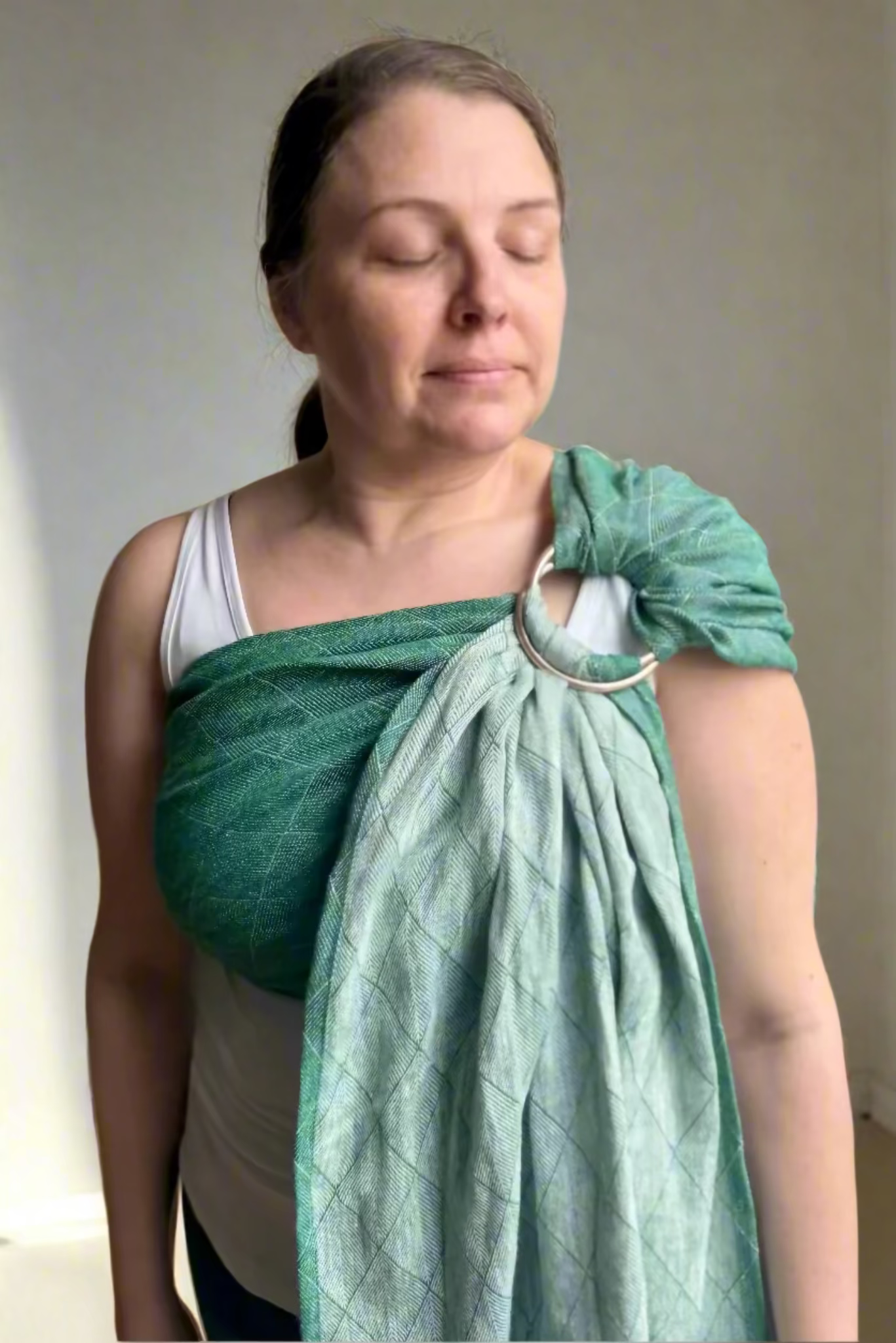 Woman wearing a green woven wrap around her shoulders indoors.