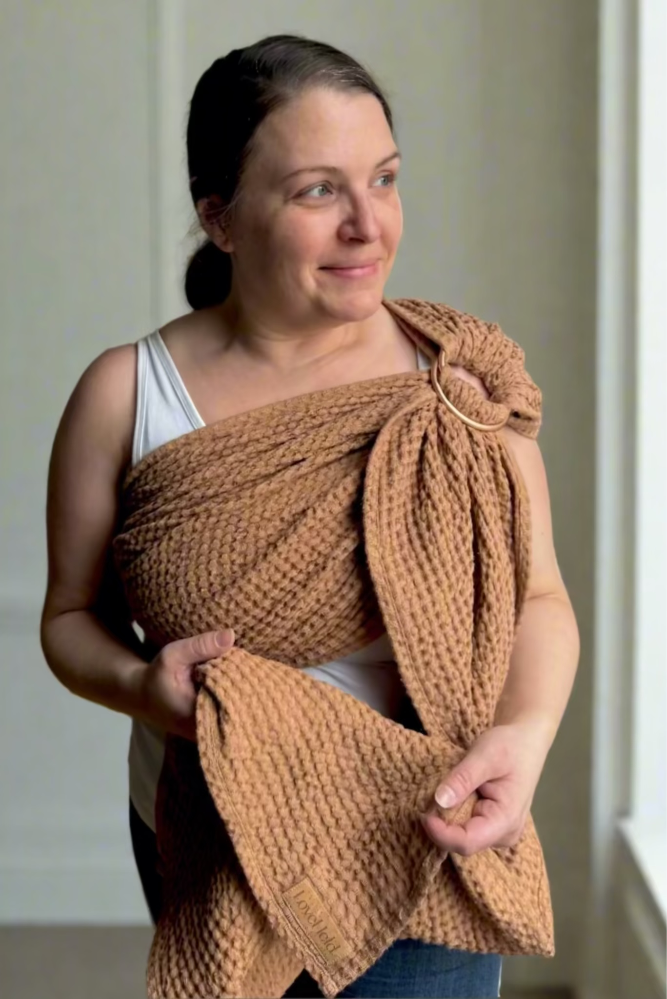 Woman wearing a brown knitted wrap over her shoulders indoors.