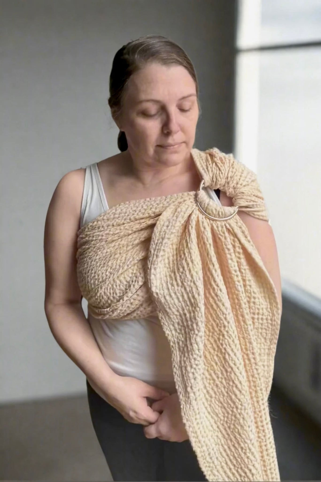 Woman wearing a buttercream woven wrap over her shoulder indoors.