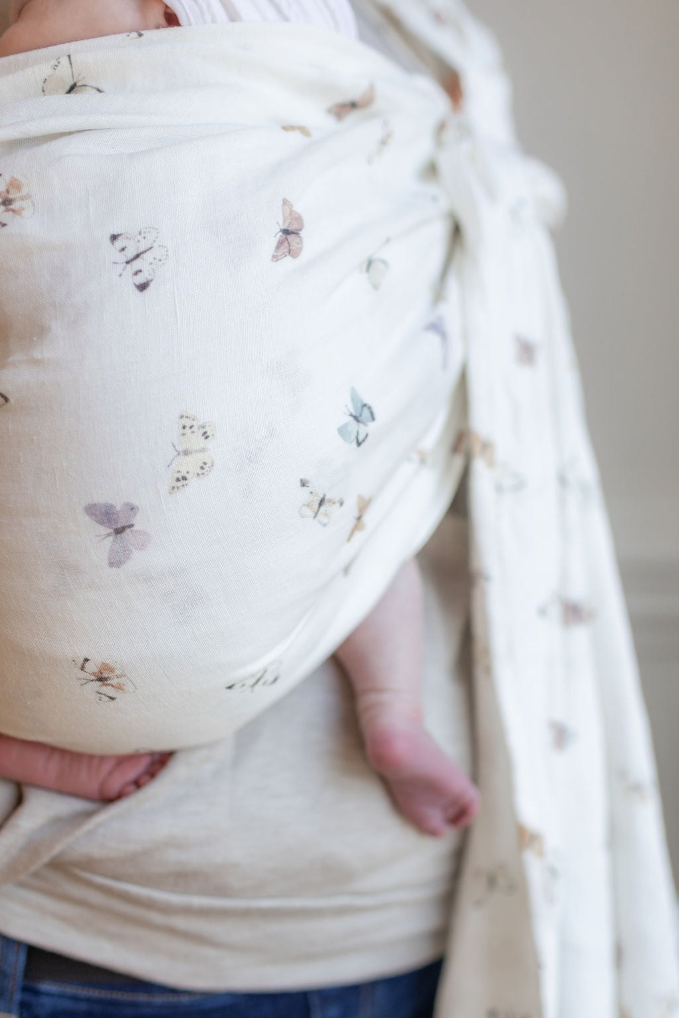 Baby wrapped in a butterfly-patterned blanket with a neutral background
