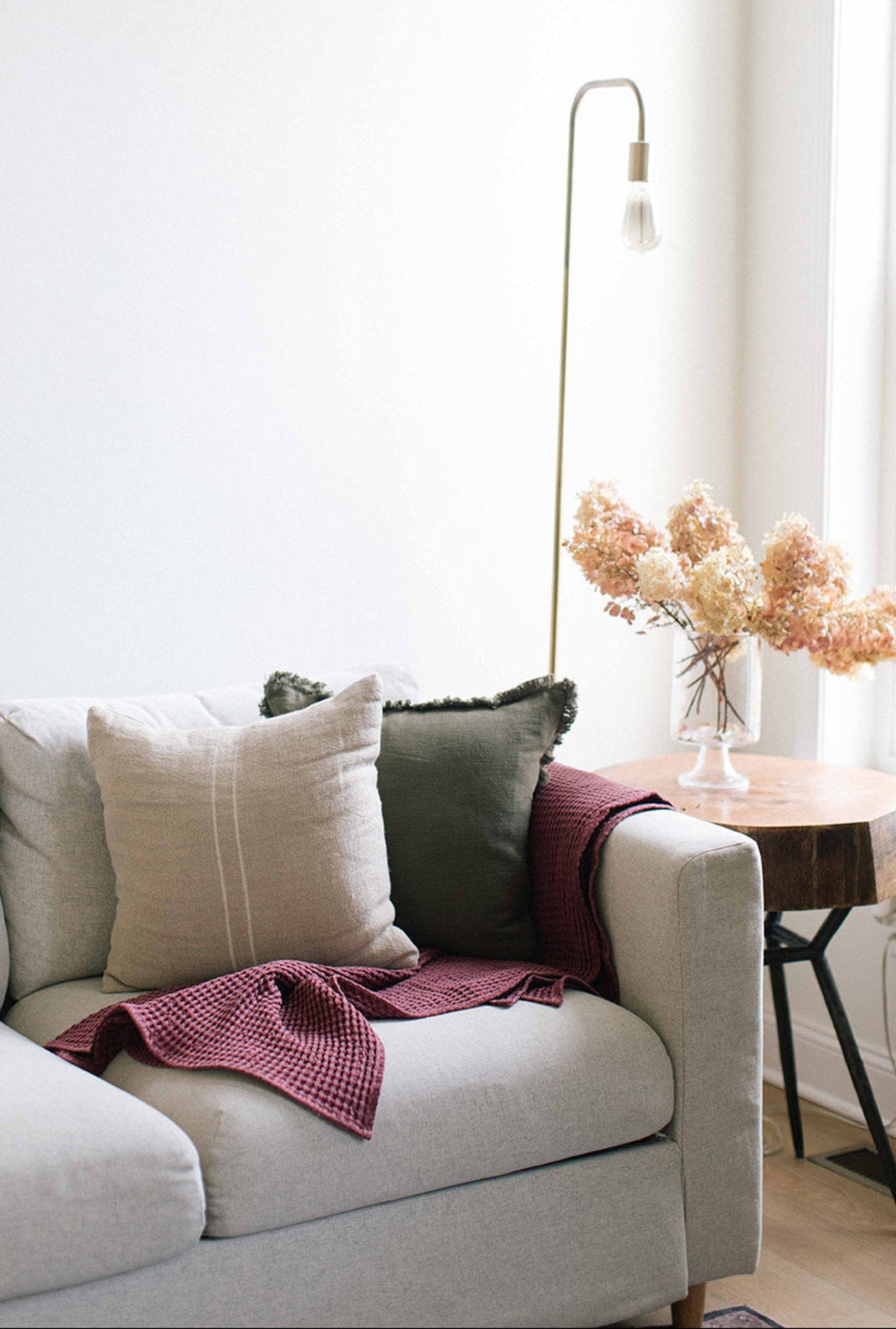White sofa with decorative pillows and a blanket in a living room setting.